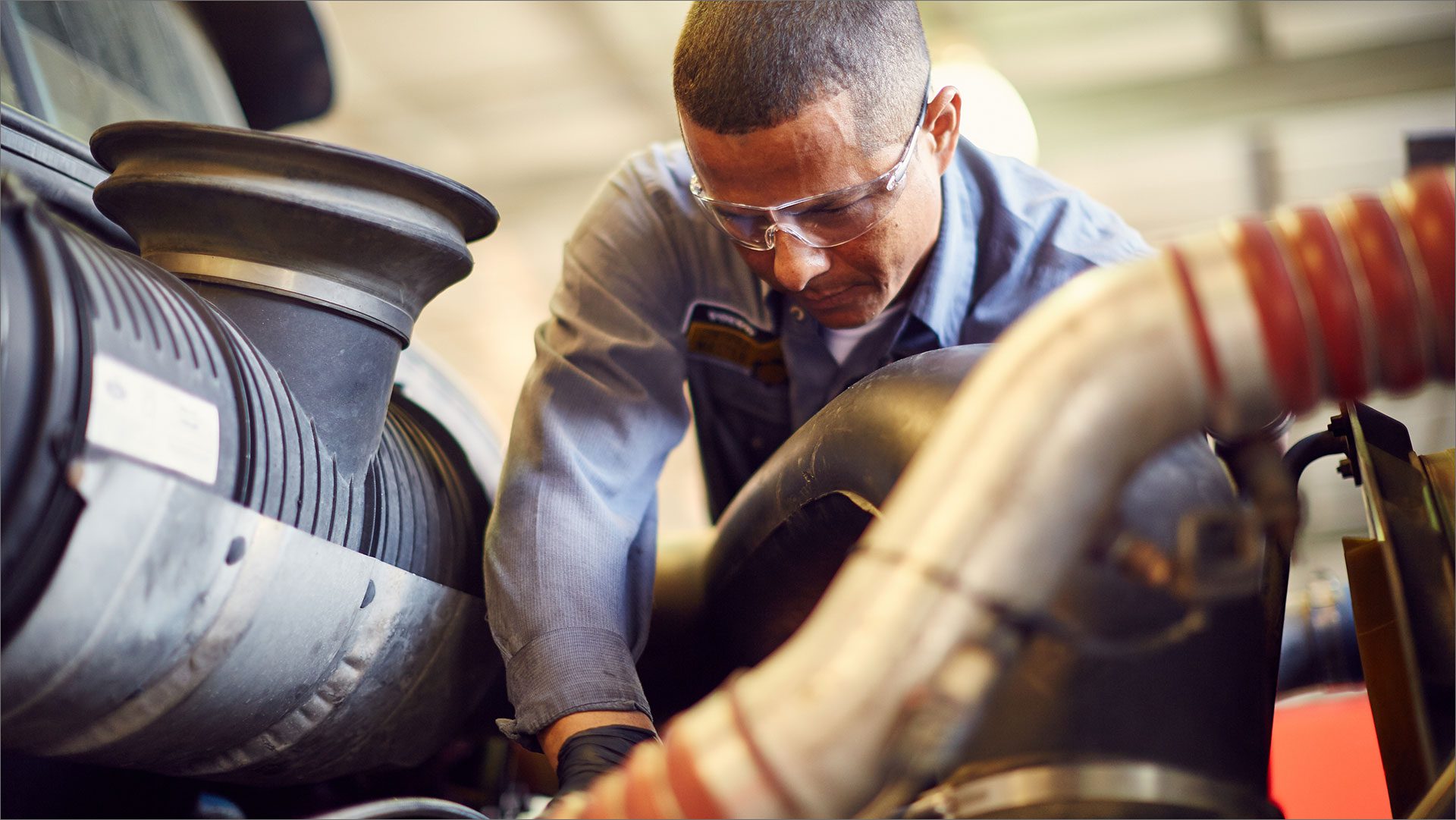 Mechanic wearing safety goggles working on an engine
